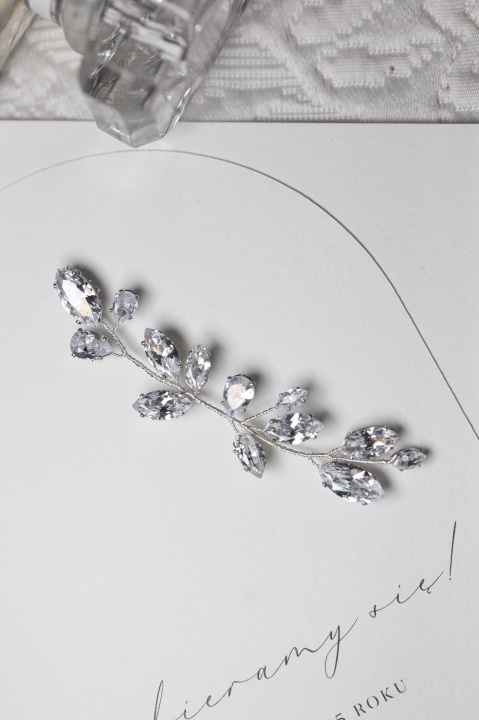 Ozdoba do włosów typu gałązka z kryształami, ułożona na papeterii ślubnej